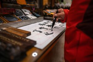 Atelier de calligraphie chinoise montrant un geste précis au pinceau sur papier blanc